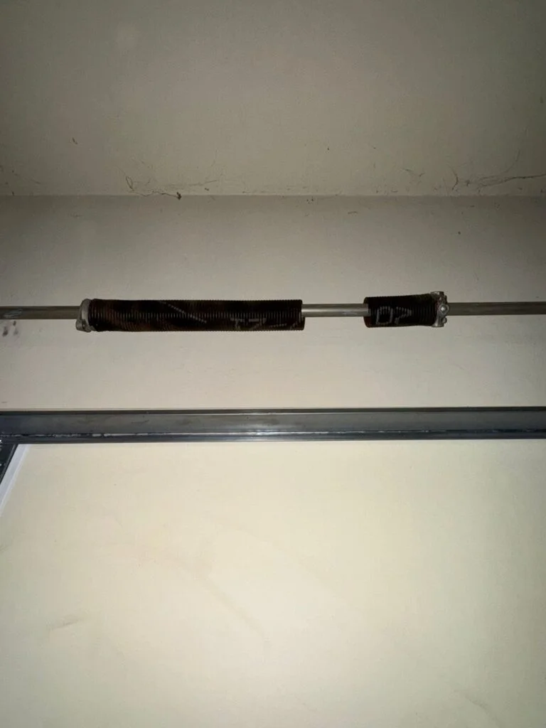 Broken torsion spring separated on the shaft above a garage door